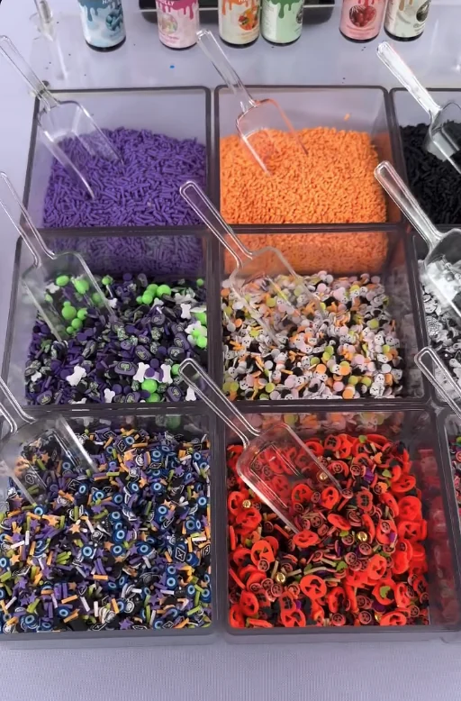 Bins of colorful Halloween mix-ins with scoops at the slime bar