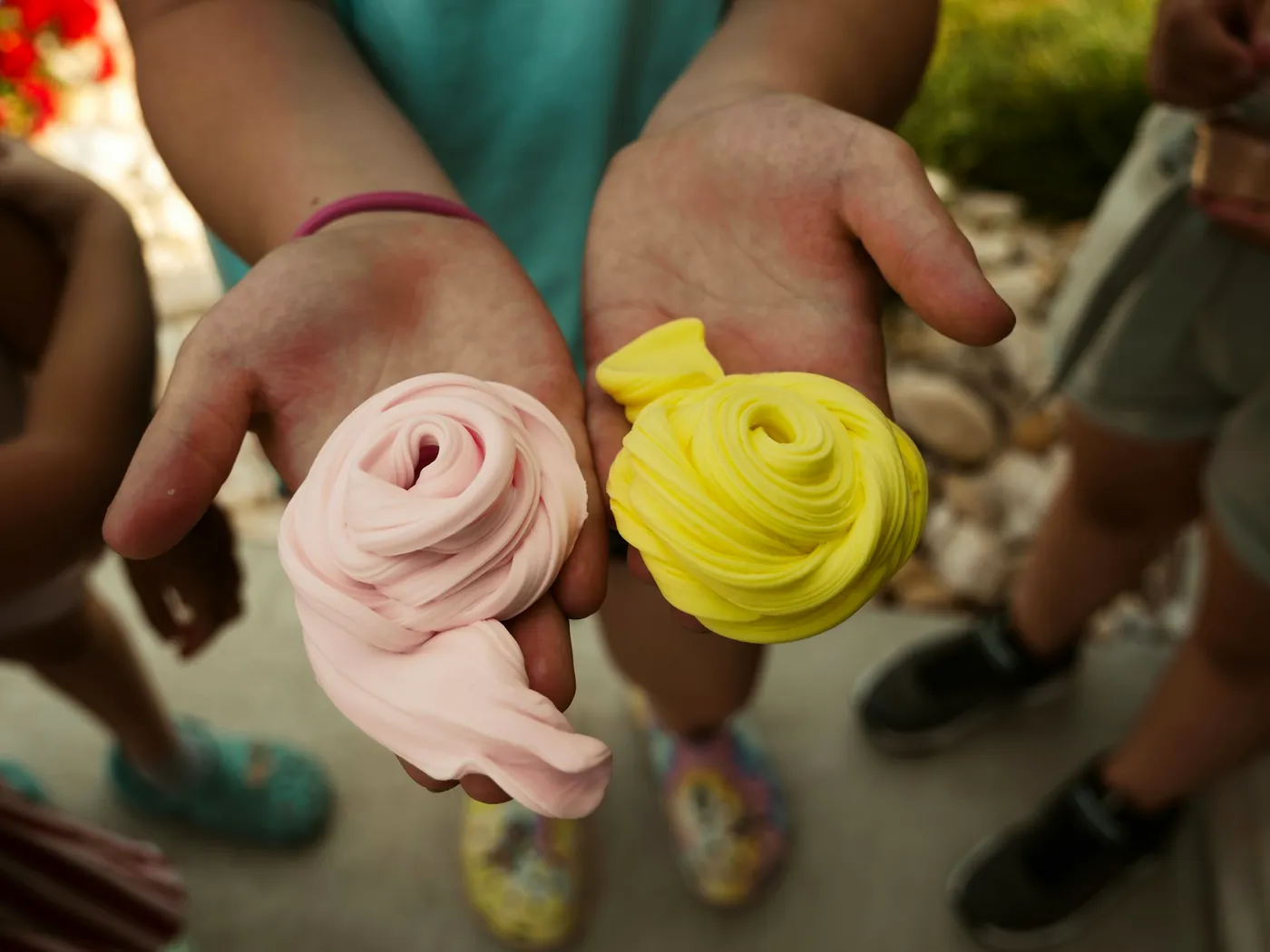 Two hands holding pink and yellow fluffy slime