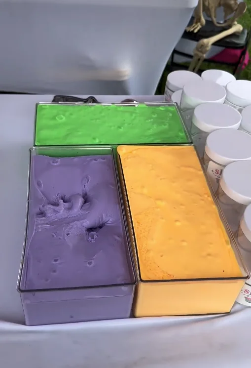 Trays of green, purple and orange slime ready to scoop